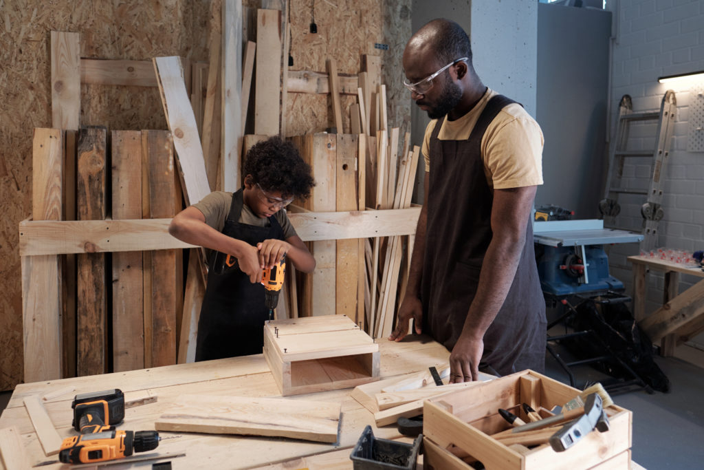 Father and Son Building Birdhouse in Workshop